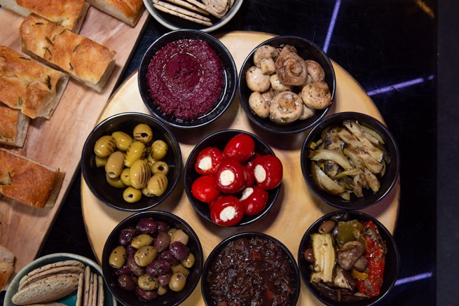 Olives, stuffed peppers and mushrooms in black bowls