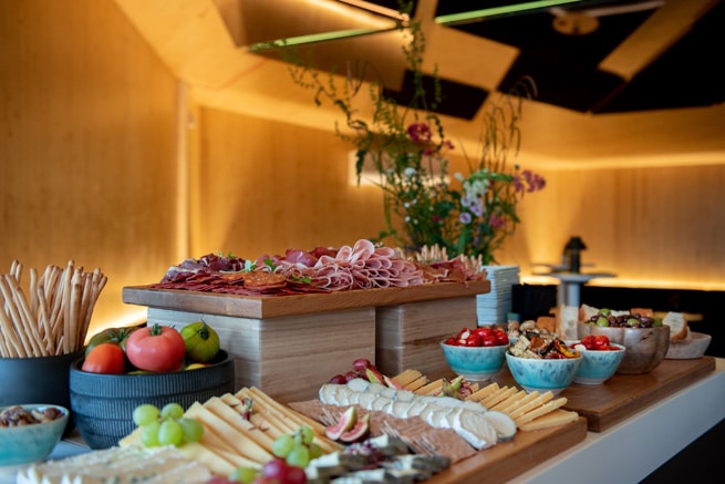 A photo of inside the VIP Oceanbird lounge. Image shows a charcuterie board with a variety of meats, cheeses, tomatoes and more on display